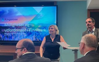 Anita Hall fra Norsk Bergindustri og Brede Edvardsen fra Norsk Arbeidsmandsforbund står foran en skjerm som viser teksten "Kingsrose - Muligheter og utfordringer i Finnmark" under et møte. Flere personer sitter i forgrunnen og lytter. Foto tatt i et moderne møterom.