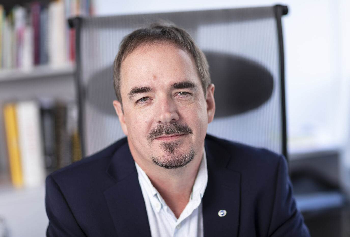 Portrett av Brede Edvardsen, leder i Norsk Arbeidsmandsforbund, sittende på en kontorstol med bokhyller i bakgrunnen. Han ser direkte mot kameraet med et rolig uttrykk.