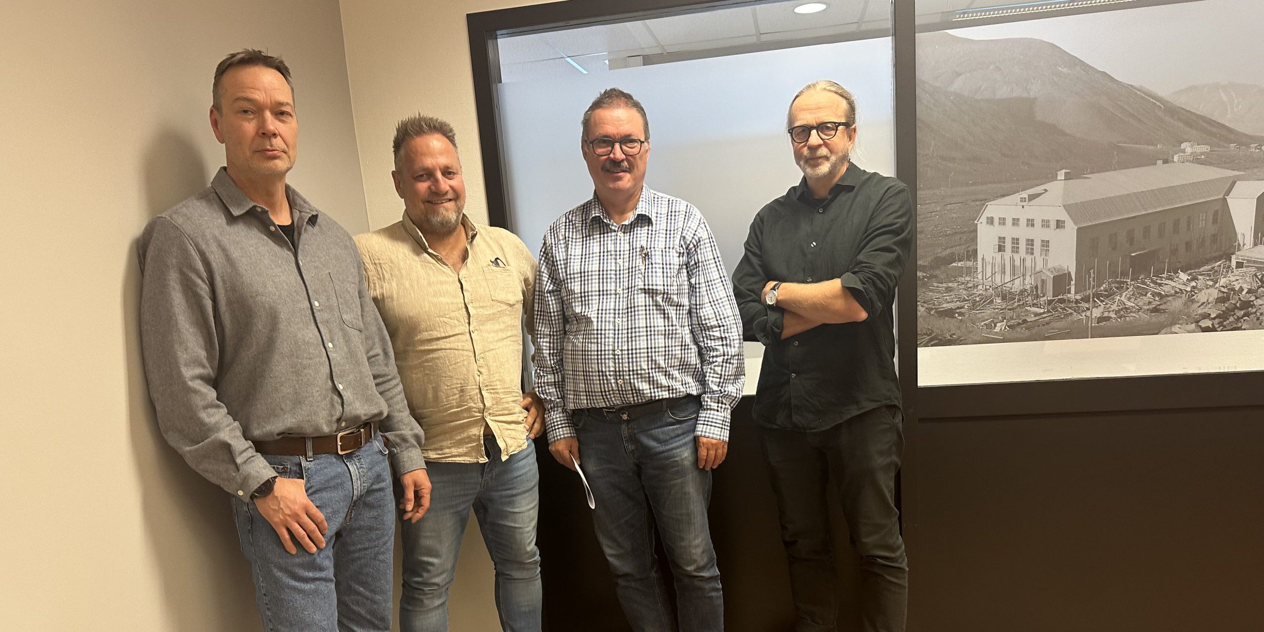 Rune Mjelde, Frank Toks, Svein Jonny Albrigtsen og Arne Presterud står ved siden av hverandre inntil en vegg og smiler.