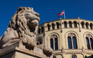 Nærbilde av den ene steinløven foran hovedinngangen til stortinget.