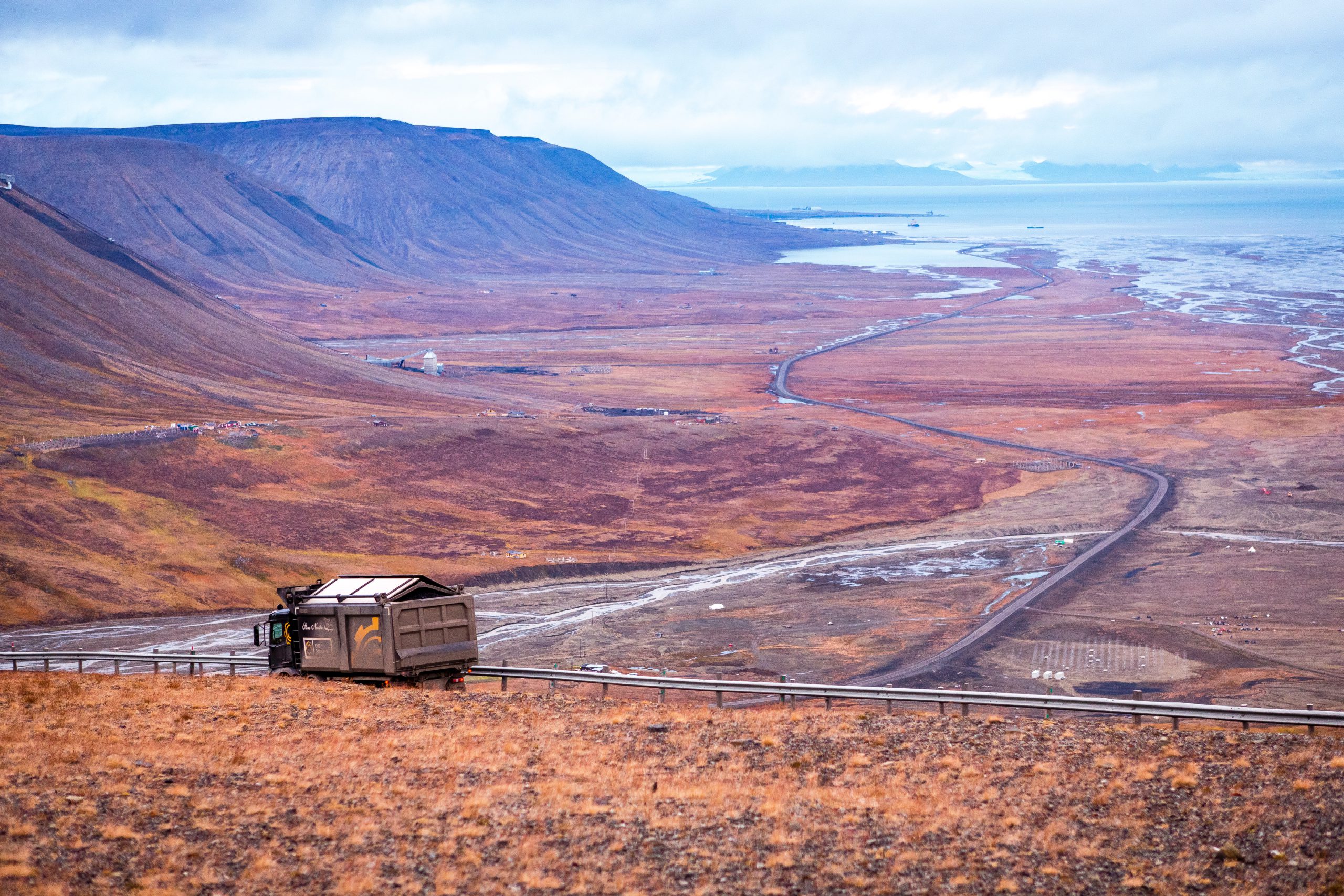 Utsikt over Adventdalen-fjorden ovenfra kullgruve nummer 7. Lastebil frakter kull mot havnen, arktisk tundra på Svalbard eller Spitsbergen, Nord-Norge.